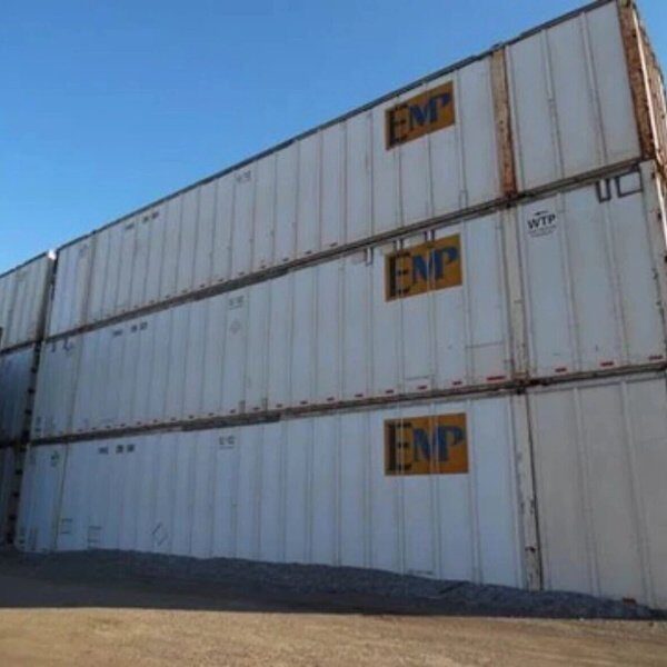 Stacks of coloured shipping containers in a port yard at first light